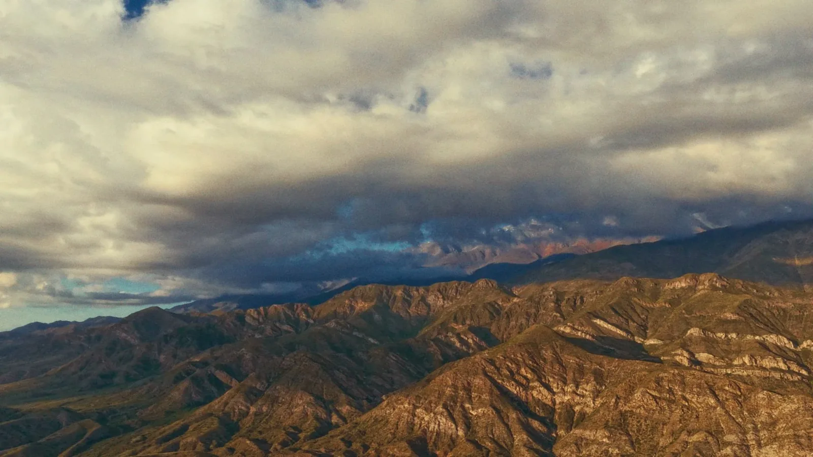 Montañas áridas bajo cielo tormentoso con nubes dramáticas