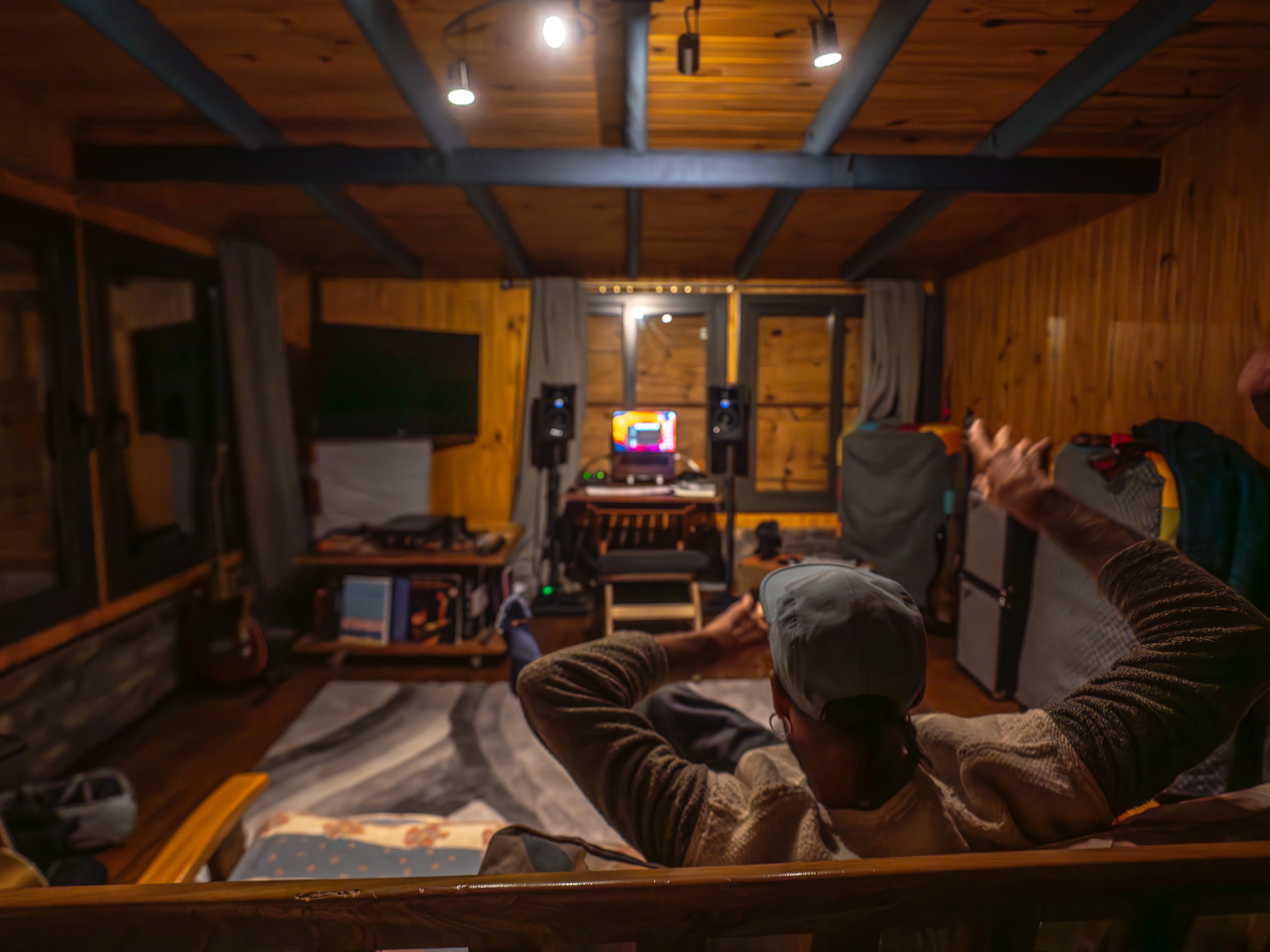 Interior cálido del estudio de noche, música en el monitor y vigas de madera vistas