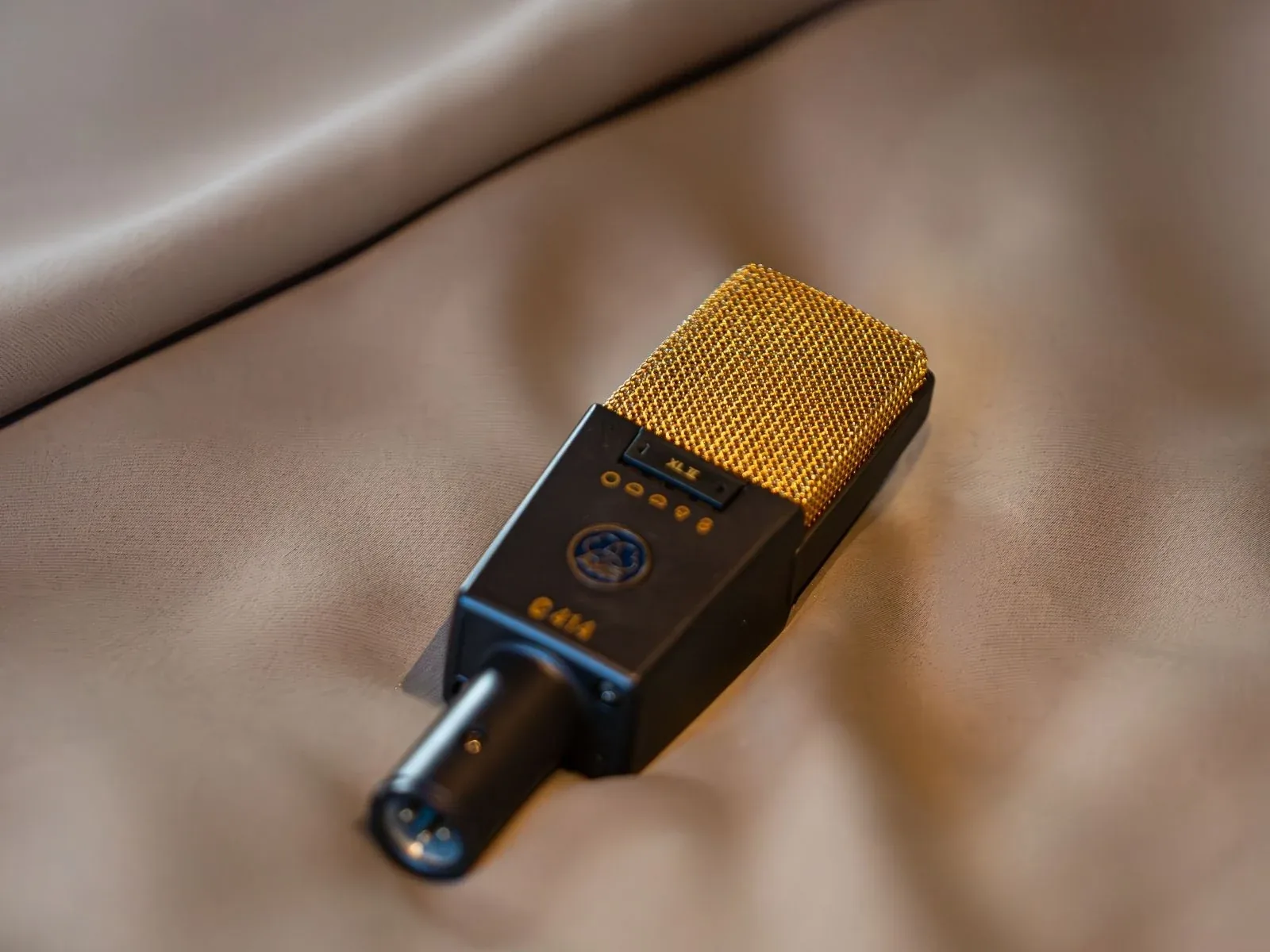 Micrófono AKG C414 dorado sobre tela beige