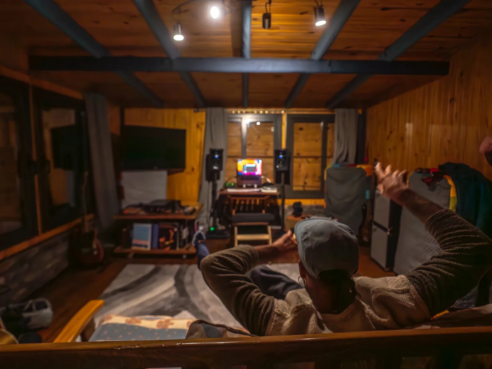 Interior cálido del estudio de noche, música en el monitor y vigas de madera vistas