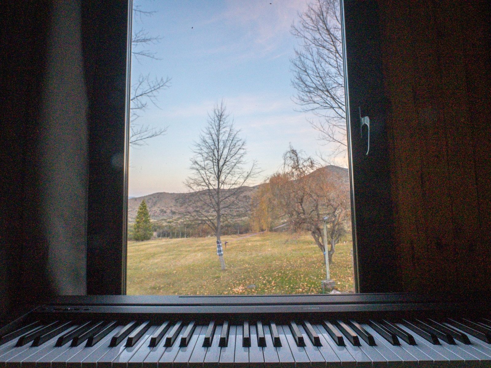 Piano de frente con ventana y paisaje de montaña al fondo